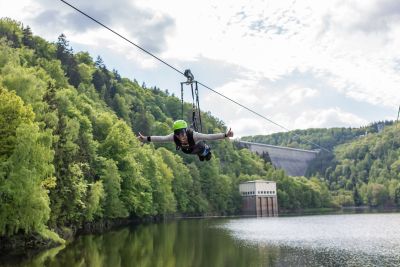 Eine Person "fliegt" am Drahtseil befestigt über den Stausee. 