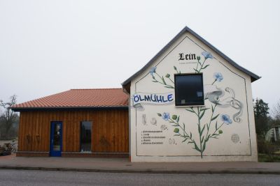 Giebelfassade mit einem großen Bild von Lein. Daneben der Schriftzug Ölmühle.