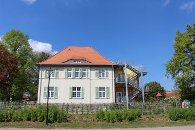 Saniertes Gebäude: Zwei Etagen, helle Fassade, hellgrüne Fensterläden.