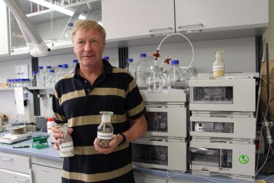 Das Bild zeigt Prof. Dr. Reinhard Paschke in einem Labor, in beiden Händen hält er jeweils ein Glas. (Foto: Ministerium der Finanzen LSA)