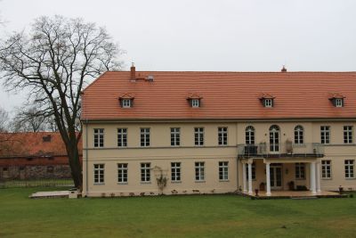 Saniertes Gutshaus mit Hellgelber Fassade und rotem Dach. Den Eingang zieren Säulen. Darüber befindet sich ein Balkon. Um das Haus herum befinden sich Grasflächen. Foto: Landesministerium der Finanzen Sachsen-Anhalt