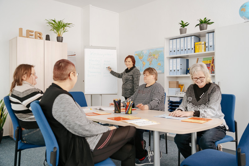 Das Bild zeigt mehrere Personen an einem Tisch. 