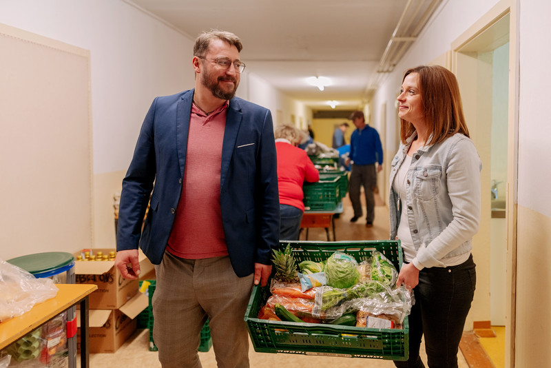 Das Bild zeigt Stefanie Märtens und einen Mann, der gemeinsam mit ihr Waren trägt. 