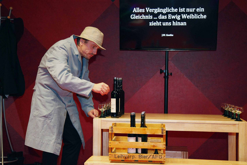 Schauspieler ordnet während der Aufführung Gläser und Flaschen an