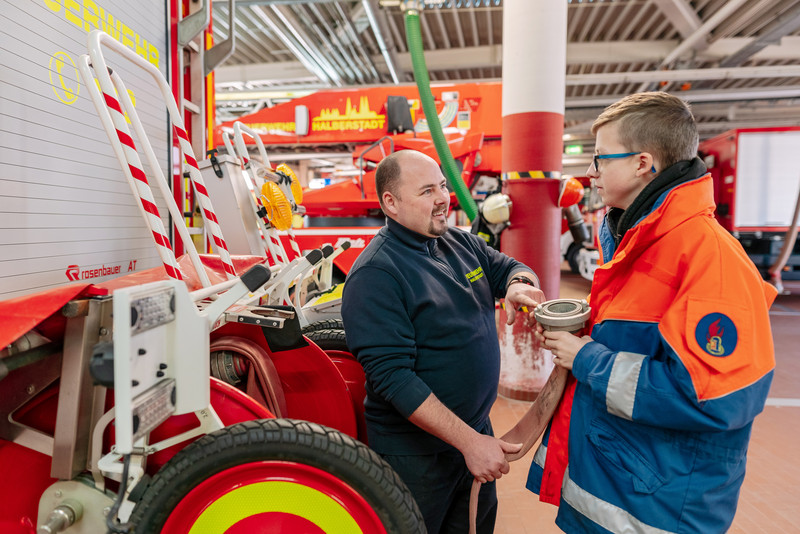 Das Bild zeigt einen Praktikanten im Gespräch mit seinem Betreuer bei der Feuerwehr. 