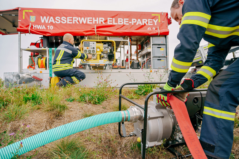 Das Bild zeigt die beschafften Geräte und zwei Feuerwehrmänner. 