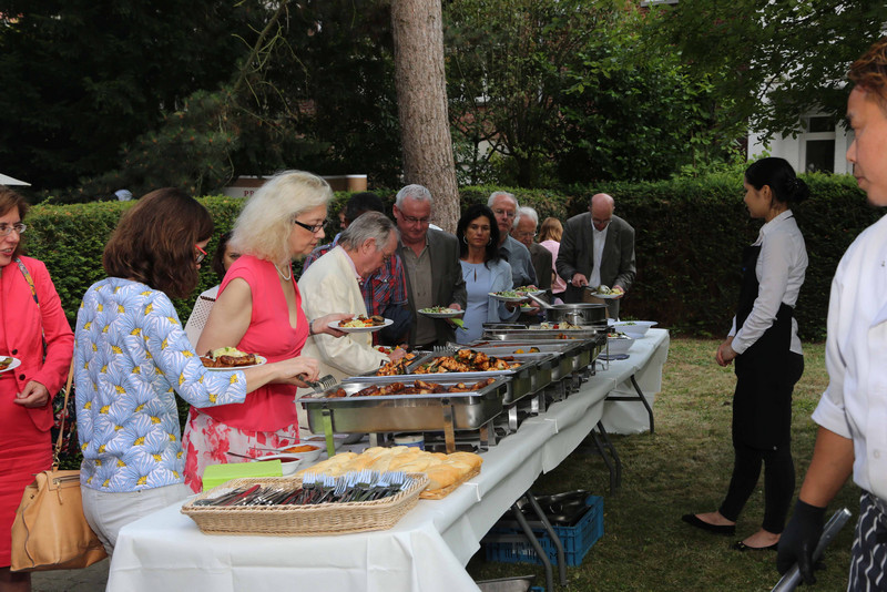 Gäste stehen am Buffet im Garten der Landesvertretung